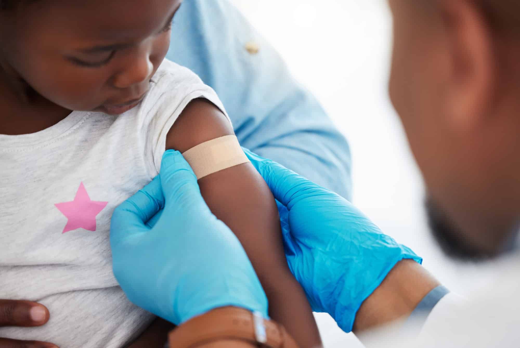 Doctor, healthcare worker and medical professional with plaster on arm of sick child after covid va