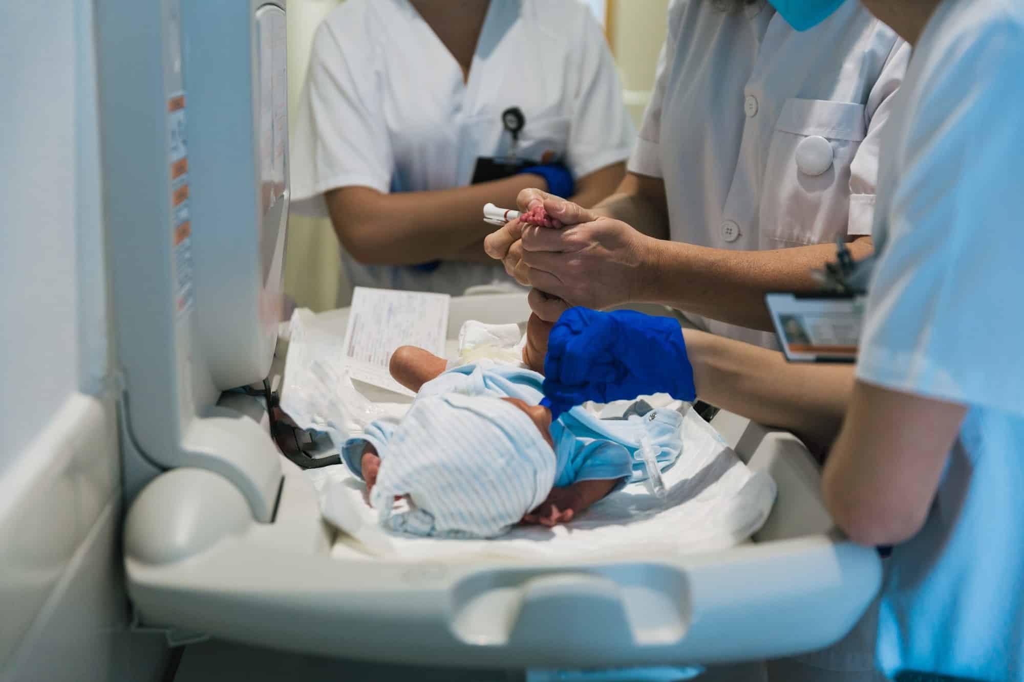 Team of professional doctors and nurses examining newborn baby at the hospital